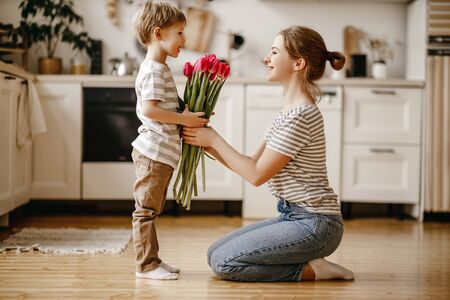 happy mother's day! child son congratulates mother on holiday and gives flowersの写真素材