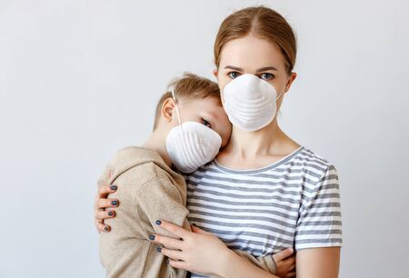 Adult woman hugging  little boy in medical masks  during coronavirus epidemic against gray backgroundの写真素材