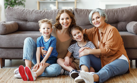 Full body mother and grandmother with kids smiling and looking at camera while sitting on floor near...