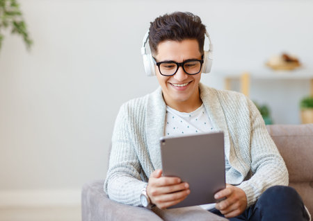 Happy ethnic man watching movie on tablet