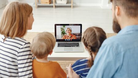 From above young parents and children resting   using laptop to speak with senior woman at home
の写真素材