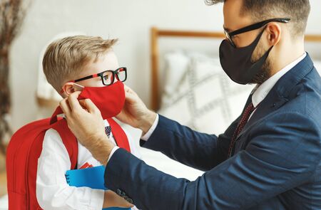 businessman father accompanies his little son to school putting on a mask to protect and prevent coronavirusの写真素材