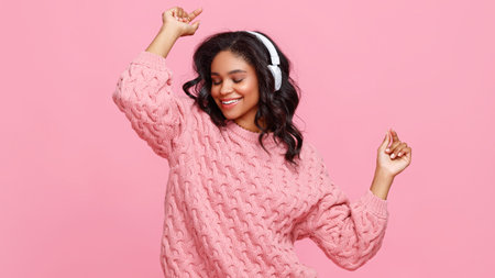Optimistic young ethnic woman in headphones smiling and snapping fingers while listening to music...