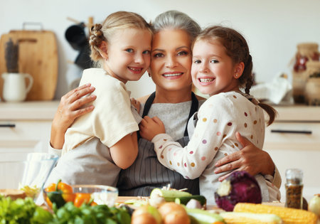 Happy family: cute little girls in aprons hugs happy grandmother in preparation of healthy...