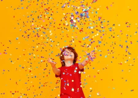 happy birthday! ginger child boy with confetti on colored yellow backgroundの写真素材