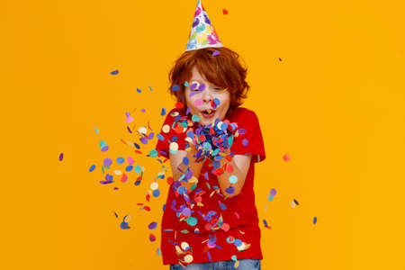 ginger child boy with confetti on colored yellow backgroundの写真素材