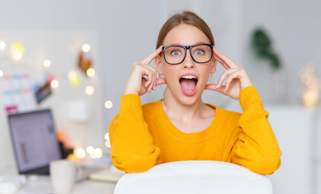 Excited young female with opened mouth touching head and looking at camera in astonishment