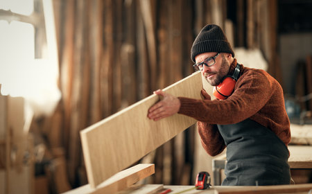 brutal man carpenter in knitted hat working in a workshopの写真素材