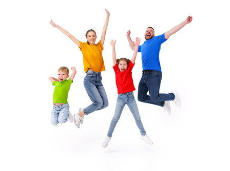 Positive family: couple and kids jumping with outstretched arms above ground in studio on white...