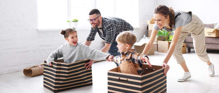 Playful family: parents riding kids in boxes and having fun during moving in new spacious apartmentの写真素材