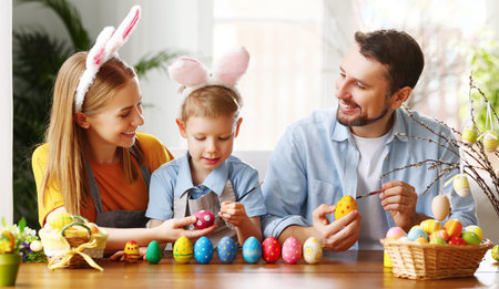 Happy family: father, mother and son wearing bunny ears headbands sitting at table at home and...