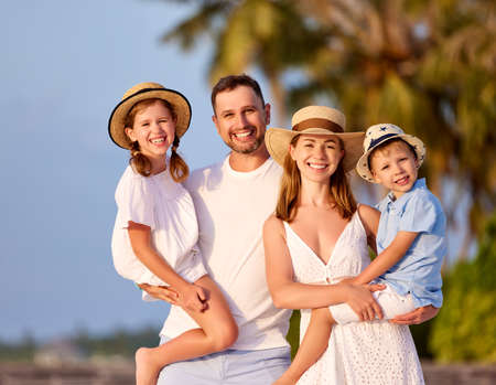 Cheerful family: parents with cute son and daughter smiling happily and looking at camera while spending summer holidays together in countrysideの写真素材
