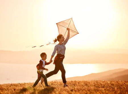 Happy family mother and child son launch a kite on nature at sunsetの写真素材