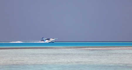Modern seaplane gliding on surface of sea water against cloudless blue sky in summer