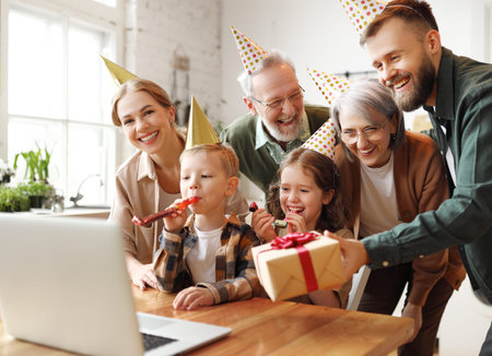 Happy big family young parents, grandparents and two kids celebrating birthday online via video call...