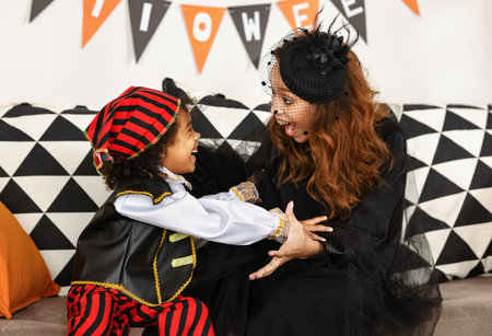 Joyful african american family mother and little boy son in Halloween costumes at home