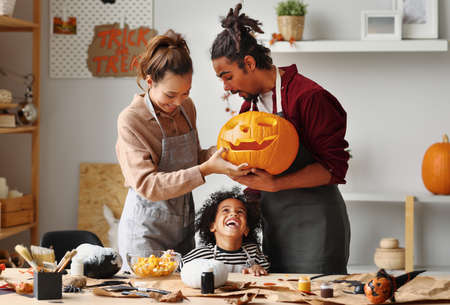 Happy family mother father and little boy son smiling while making jack o lanternの写真素材