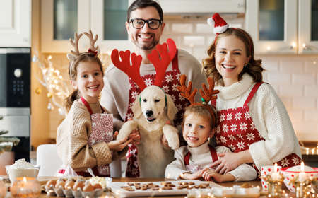 Happy family parents with two kids and golden retriever puppy while making xmas cookies at homeの写真素材