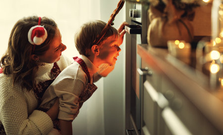 Happy loving family mother and son waiting for preparation of Christmas cookies in ovenの写真素材