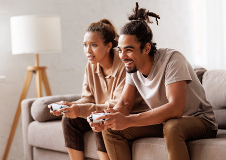 African american couple laugh and play video games together using a video game consoleの写真素材