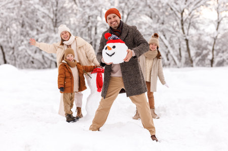 Cheerful family parents with kids in snowy winter park have fun and actively relax outdoorsの写真素材