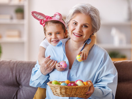 Happy family in bunny ear headbands laugh and play with eggs at home during preparation for Easter...