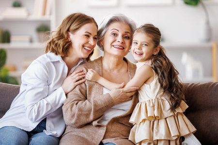 Happy multi generational family: senior woman with daughter and granddaughter on couchの写真素材