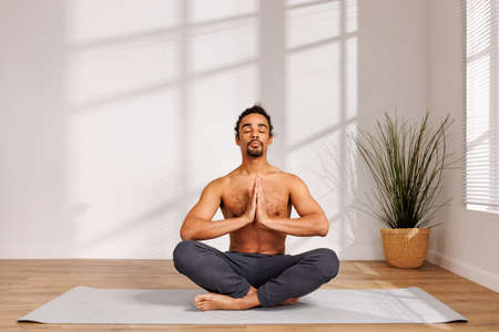 Relaxed black man meditating near potted plantの写真素材