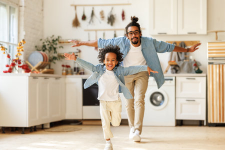 Happy funny african american family excited little boy son having fun with father at homeの写真素材