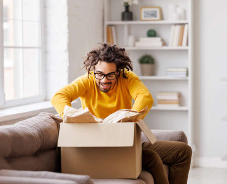Black man unpacking carton box at homeの写真素材