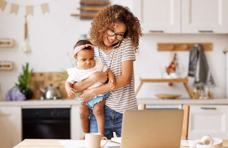 Multitasking african american self-employed mother working with baby from home on maternity leaveの写真素材