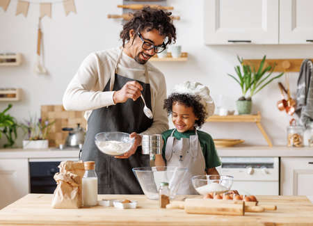 Black man and son cooking together in kitchenの写真素材