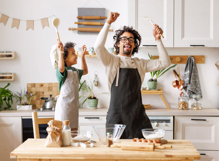 Black father and boy having fun during cooking in kitchenの写真素材