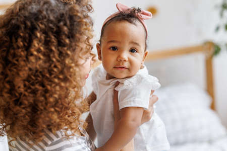 Happy, cheerful ethnic mom holds a baby daughter in her arms.の写真素材