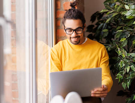 Cheerful black freelancer using laptopの写真素材