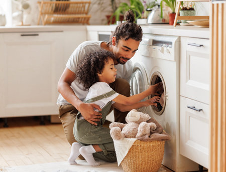 Son helping dad to load washing machineの写真素材