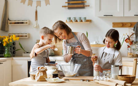 Happy woman and cute children cooking together in kitchenの写真素材