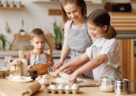 Happy woman and cute children cooking together in kitchenの写真素材