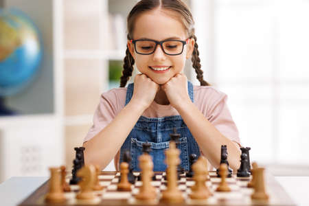 Happy smiling girl playing chess at schoolの写真素材