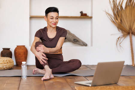 Middle aged sportswoman watching tutorial video at homeの写真素材