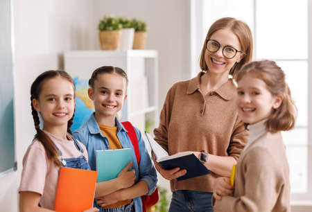 Teacher speaking with students during lesson in sunlit classroomの写真素材