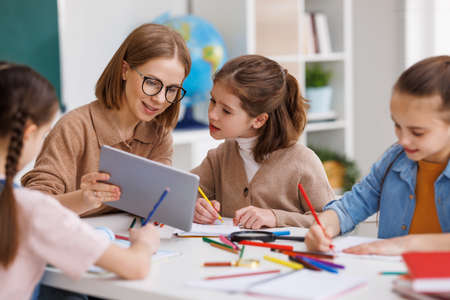 Woman with tablet teaching children at schoolの写真素材