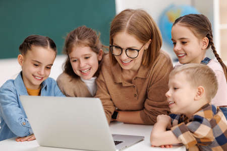 Teacher and pupils using laptop at schoolの写真素材