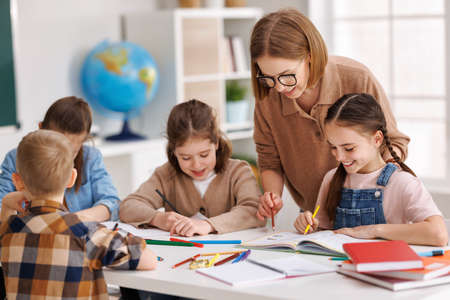 Teacher helping children with schoolwork at schoolの写真素材