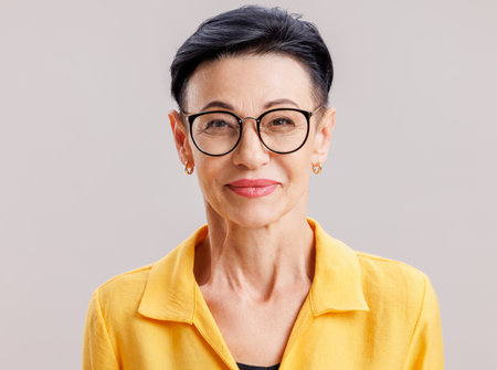 Smart mature female looking at the camera against gray backgroundの写真素材