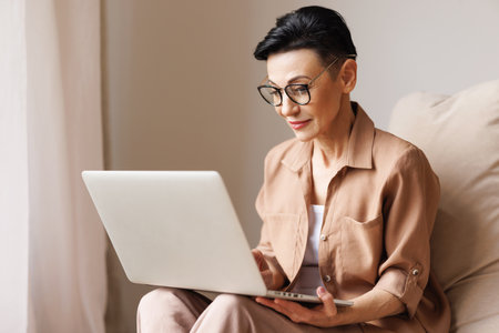 Middle aged woman using laptop at homeの写真素材