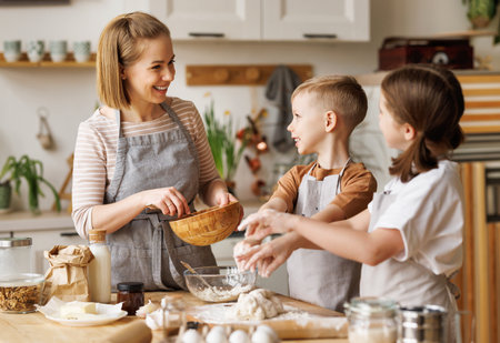 Happy woman and cute children cooking together in kitchenの写真素材