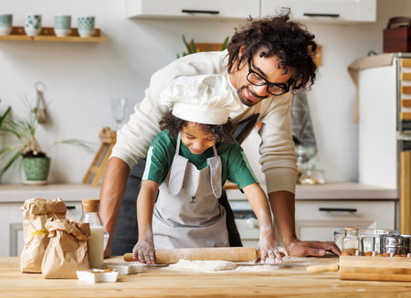 Positive black father and son cooking together