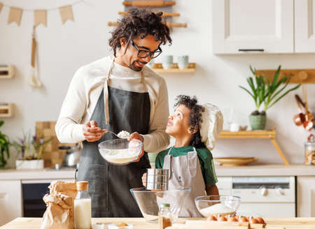 Black man and son cooking together in kitchenの写真素材