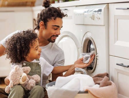 Son helping dad to load washing machineの写真素材